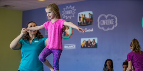 Woman helping girl on balance beam